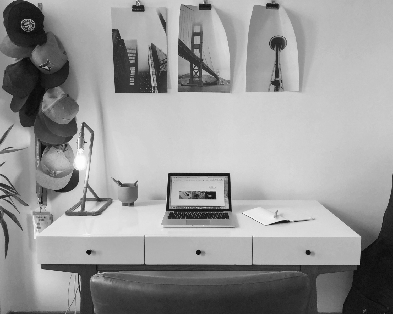 open laptop on table beside guitar bag and hanging hats