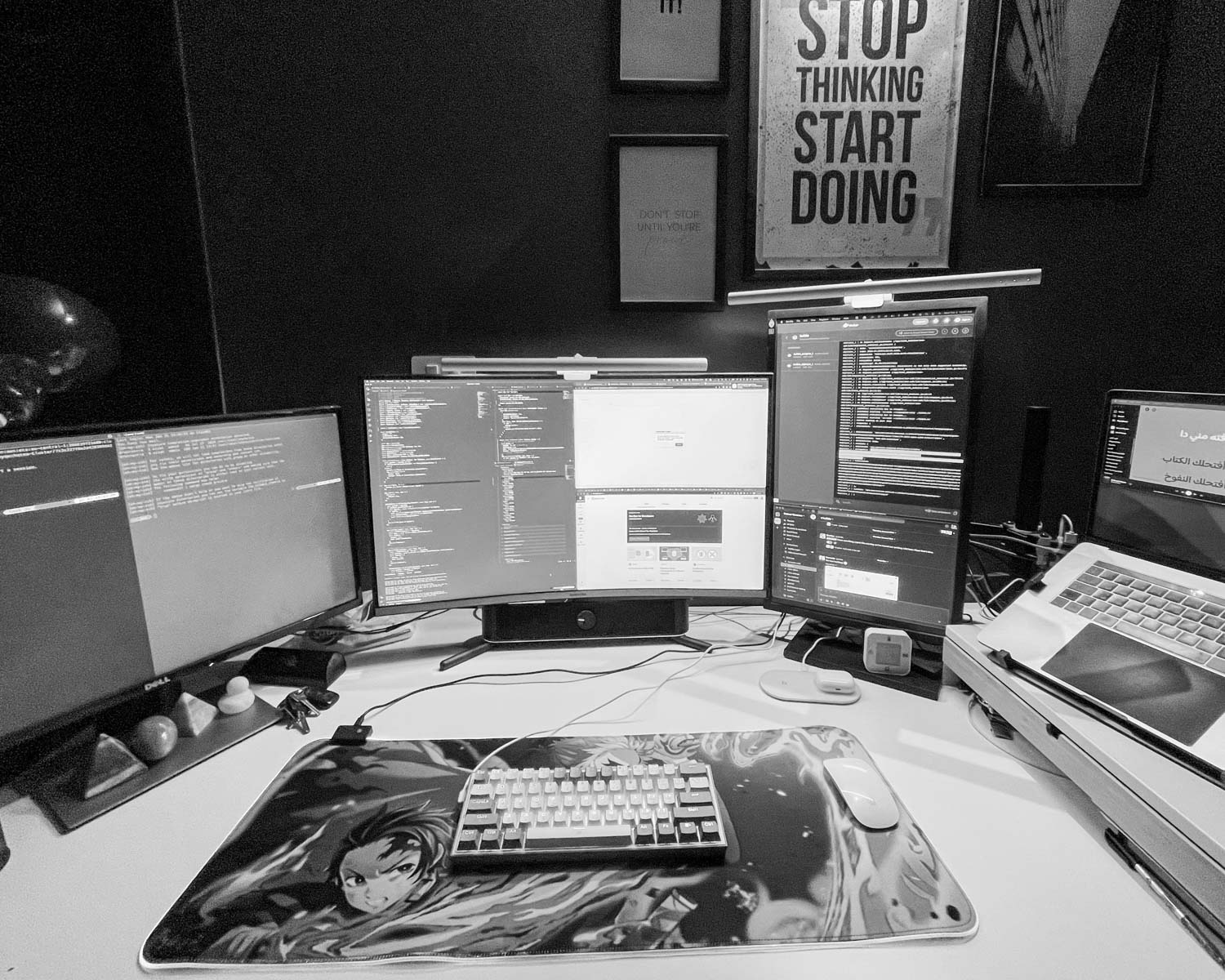a desk with three computers and a laptop on it