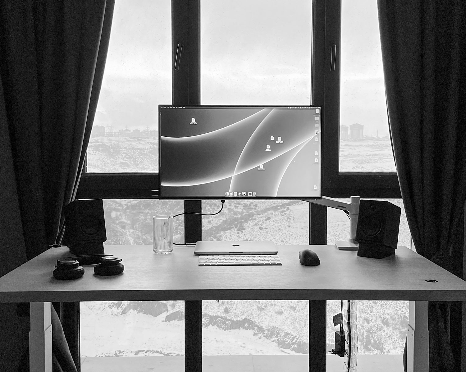 a desk with a computer on it in front of a large window