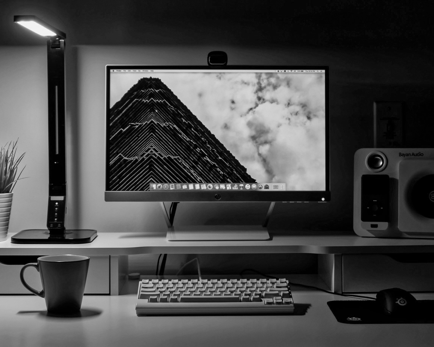 flat screen TV turned-on near keyboard, multimedia speaker, and ceramic mug on table