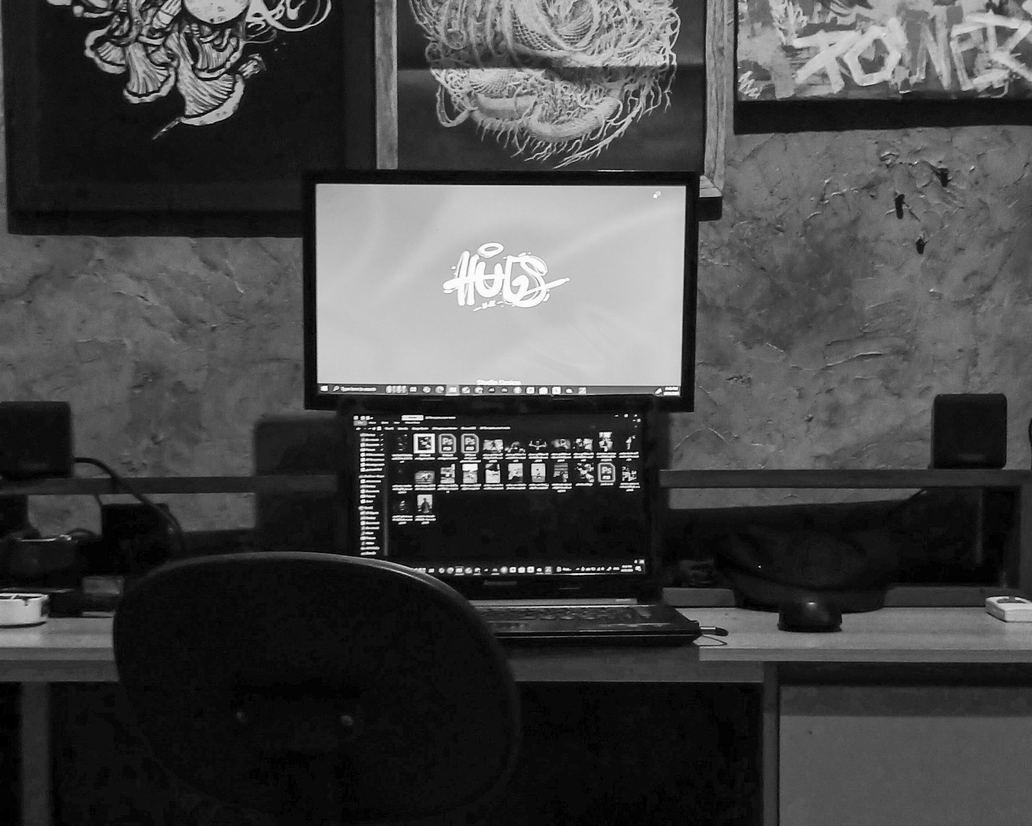 A laptop setup with artwork on the wall.