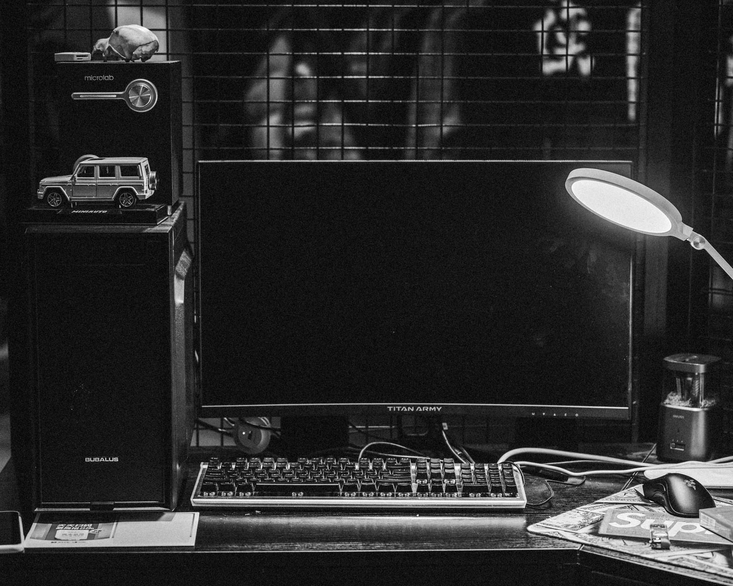 a desk with a keyboard, monitor, mouse and a lamp