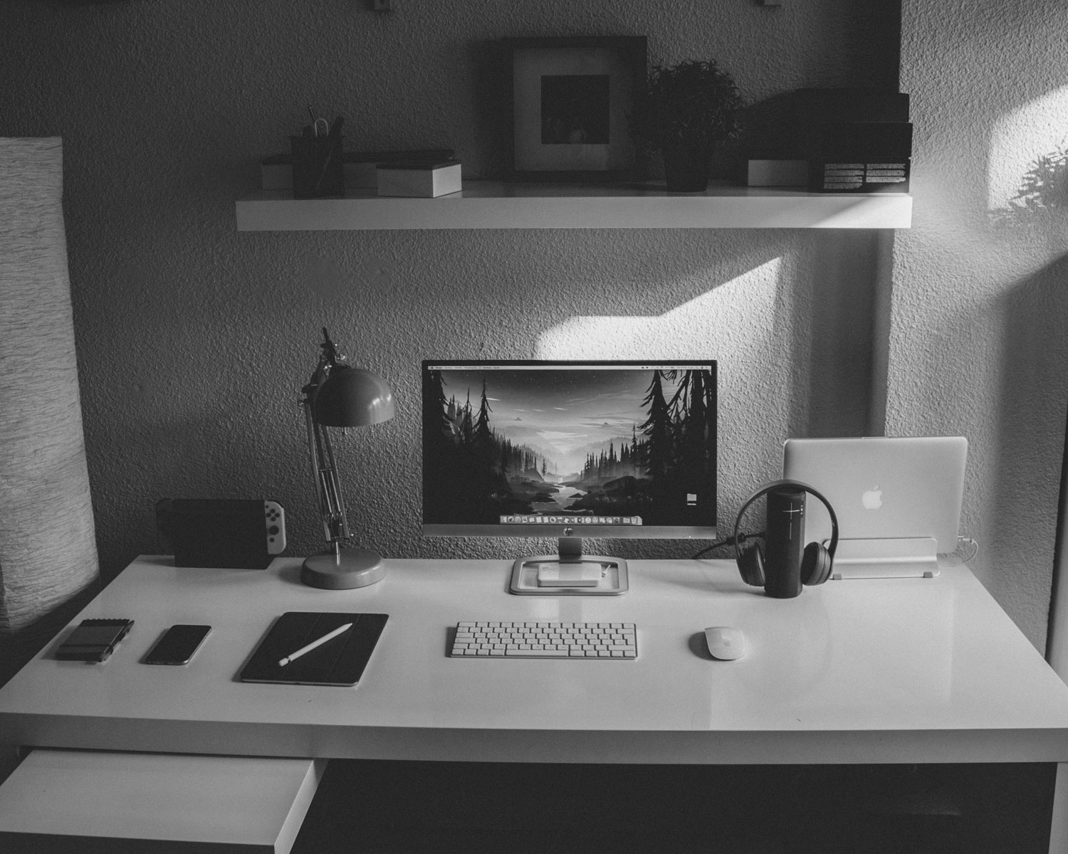 silver iMac and white cordless keyboard on white wooden table inside room