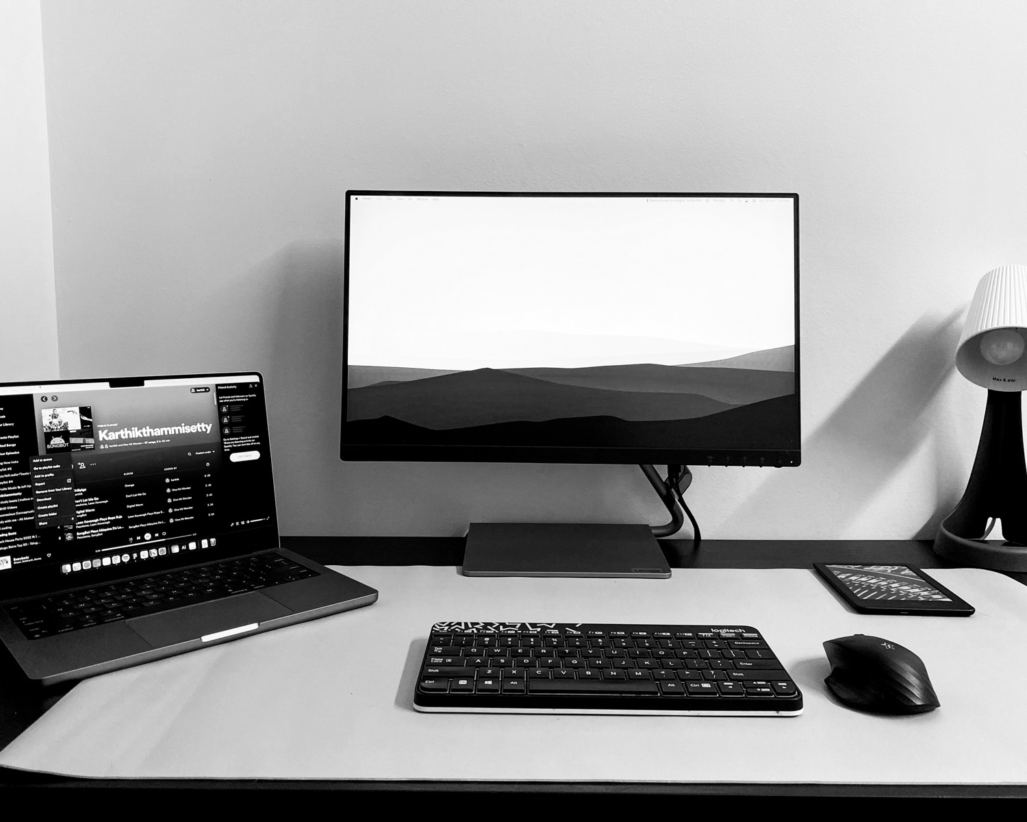 a desk with a laptop, keyboard, mouse and monitor