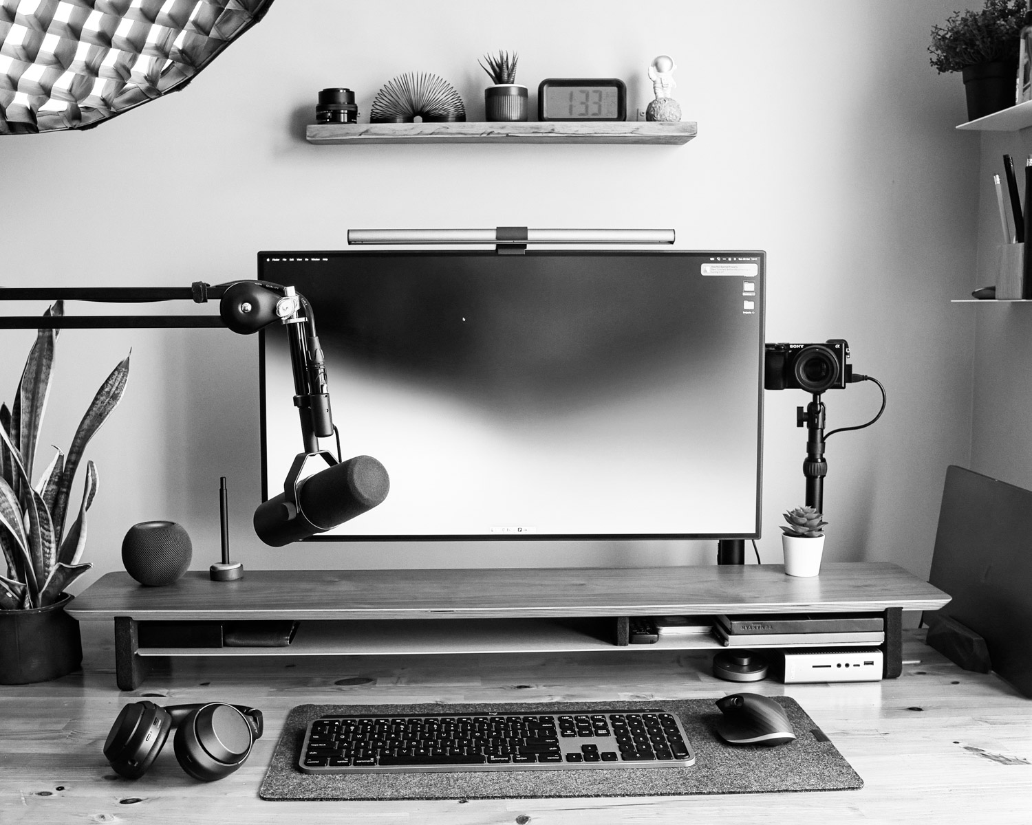 a desk with a monitor, keyboard and headphones
